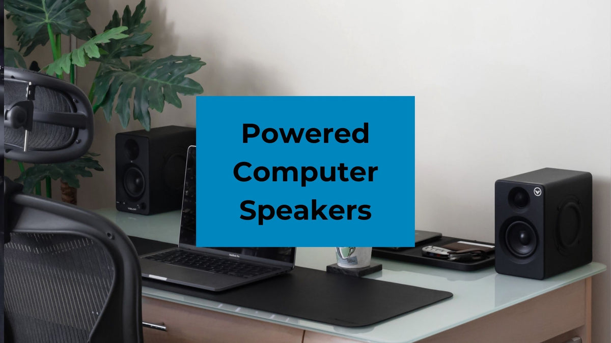 Powered Computer Speakers on a desktop with a laptop. 